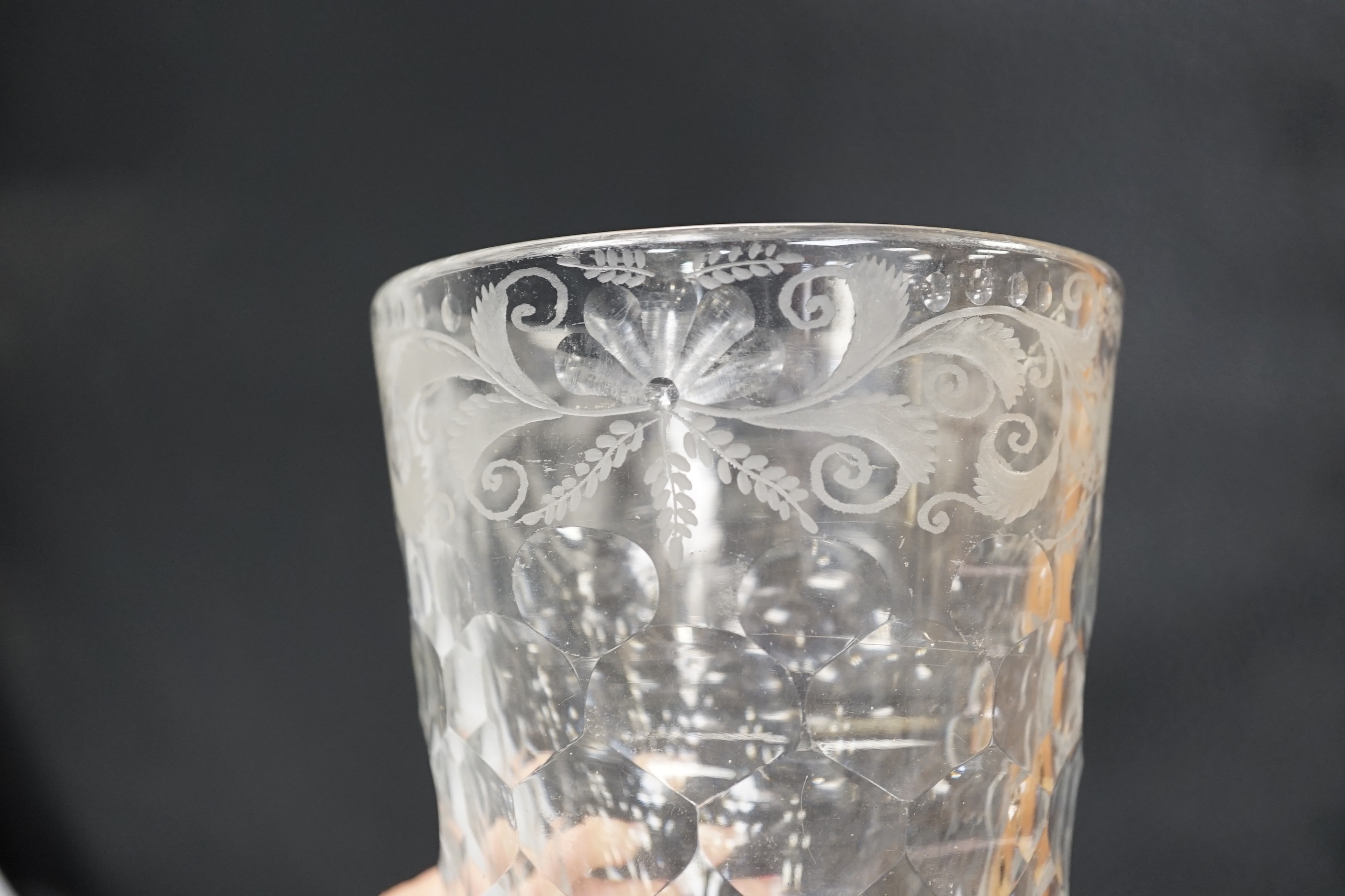 An English lead crystal 18th century faceted tumbler, in a darkish grey metal, upper decoration engraved and polished floral centre, three rows of facets running into plain facets, whole of foot polished to remove pontil